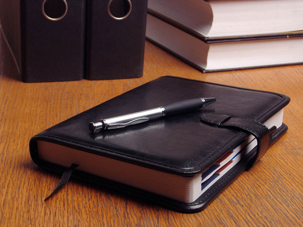 Black organizer on the office desk surrounded by documents and files;